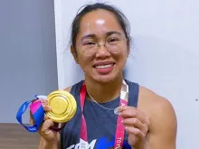 Filipina weightlifter Hidilyn Diaz proudly displays her Olympics gold medal and the Miraculous Medal, a devotional medallion depicting the Virgin Mary.